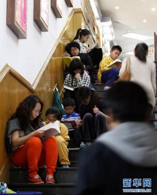 2014年4月18日，北京三联韬奋书店，人们坐在通往地下一层的楼梯上读书。新华社记者 沈伯韩摄